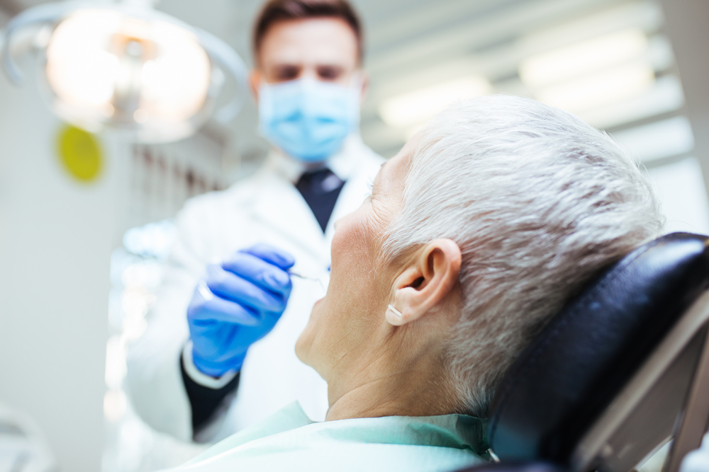 Dentist performing a TMD examination on older woman