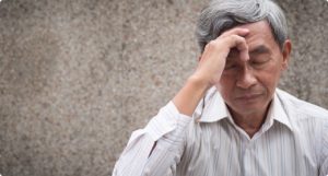 Older gentlemen touching his forehead with migraine pain
