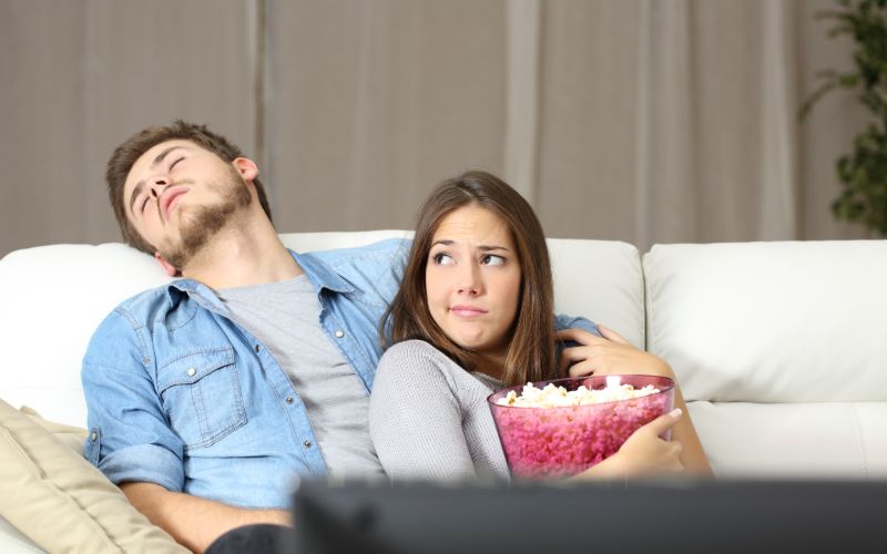 couple trying to watch a movie but one person is asleep